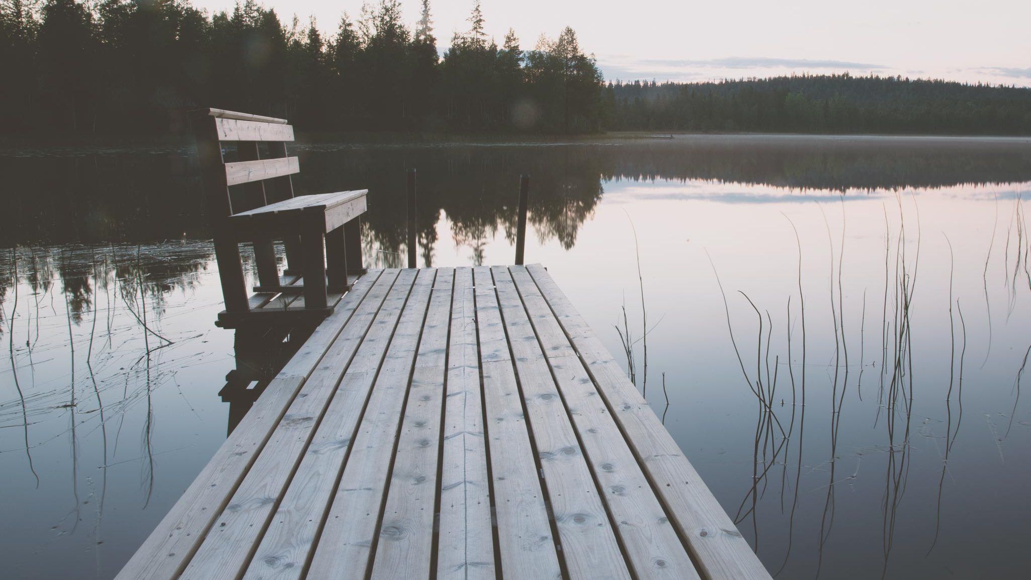 Laituri ja penkki tyynellä järvellä